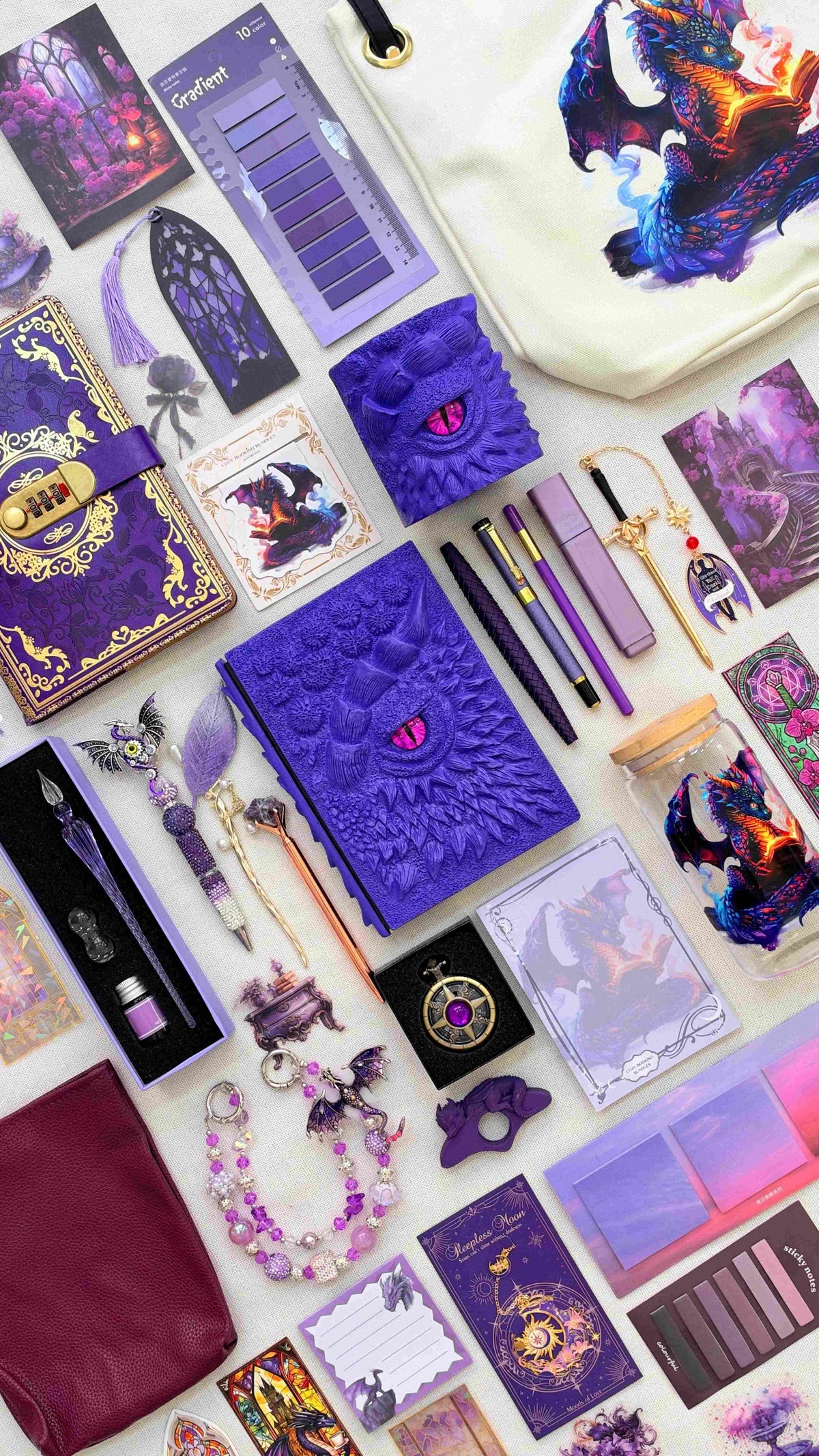 Royal Amethyst Velvet Edition dragon bookish bundle in deep purple with a sculpted dragon eye notebook and matching pen holder organizer. Flat lay includes pens, a glass dip pen and ink set, fantasy bookmarks, sticky notes, reading tabs, dragon charm, pocket watch, crossbody bag, dragon print tote bag, decorative glass jar and extra notebook.